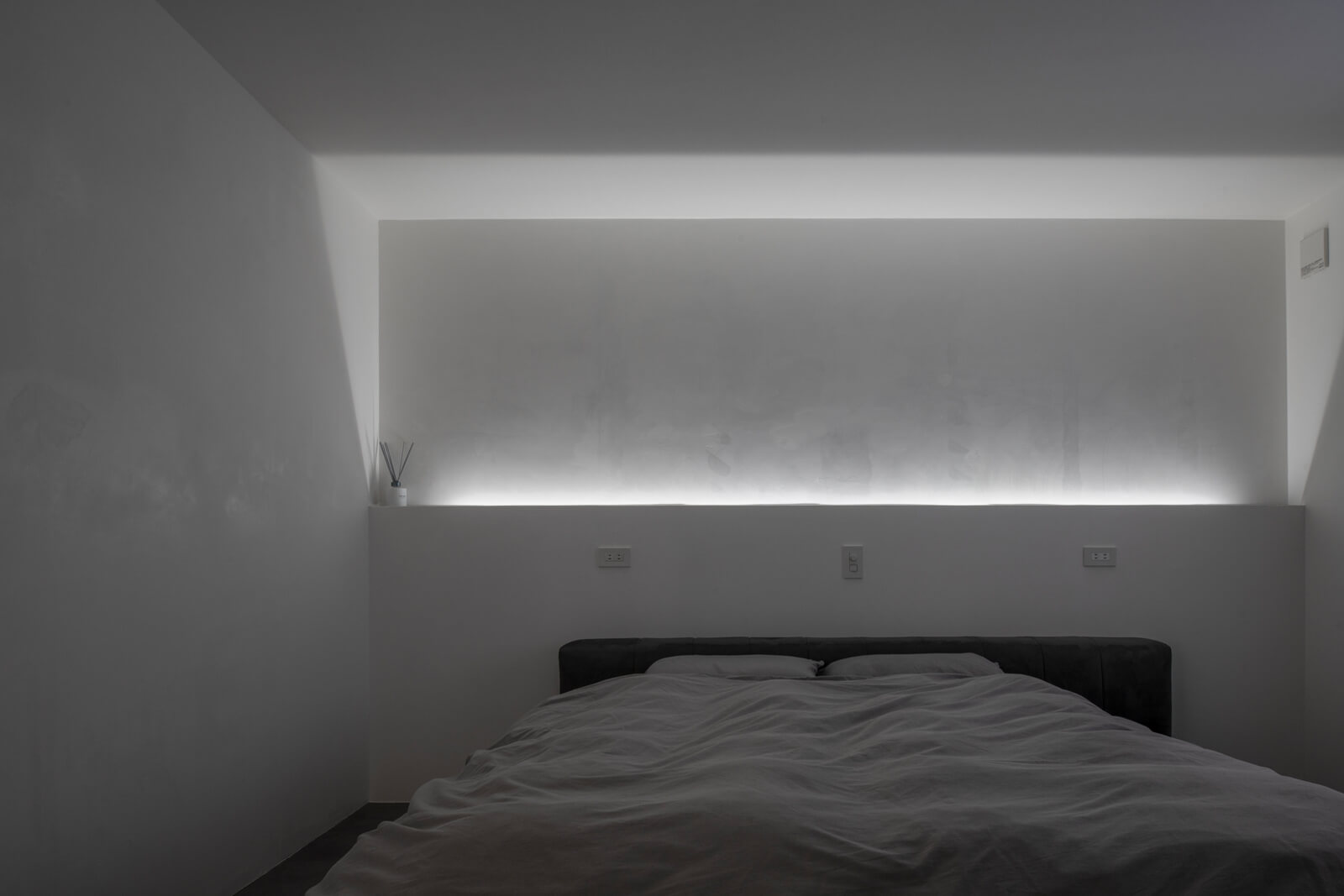 主寝室は漆喰の塗り壁の表情を引き立てる間接照明を採用。穏やかな陰影が落ち着いた夜の時間を演出する