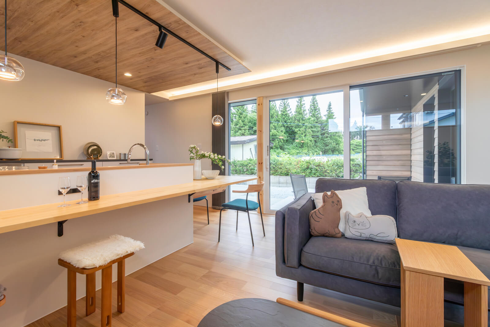 リビングの幅約4m、高さ2.2mの大開口はご夫妻の要望。敷地の奥に住まいを建築し、来訪者が玄関まで来なくてもいいようにカーポートにインターフォンを設置するなど、プライバシーを保てるように配慮した。隣家側に施した植栽も目隠しの役割を果たす