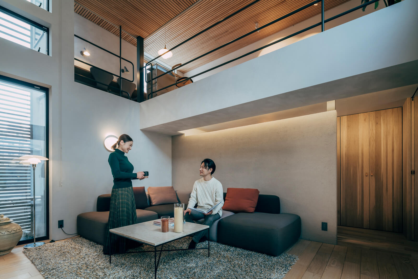 ソファーでリラックスしながら映画鑑賞をすることもあるため、天井は吸音効果のあるフェルト材貼り＋格子天井で音が反響しないようにした。リビングは吹き抜けを通じて、2階にある奥さんのワークスペース兼趣味室とつながる