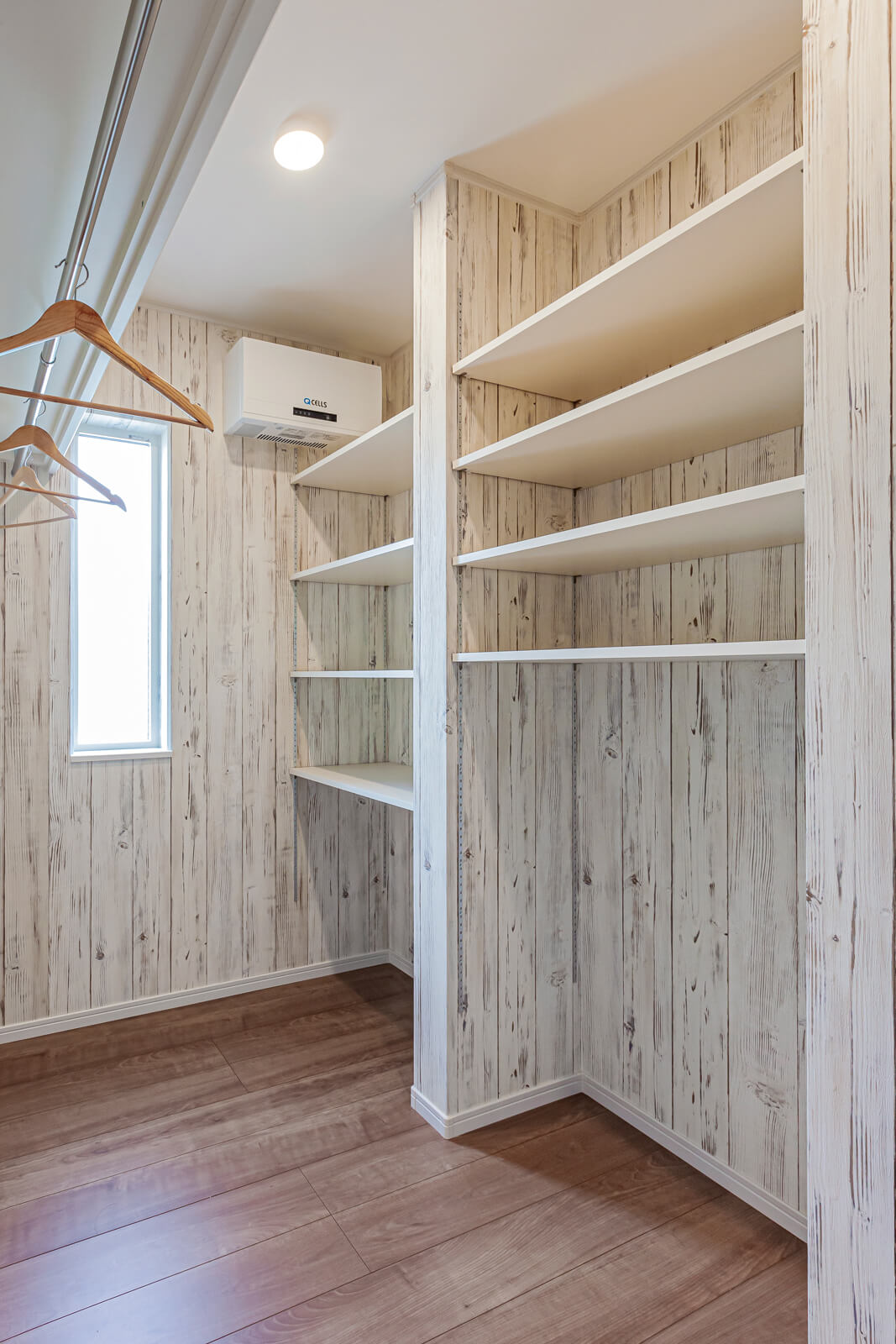 1階に設けたファミリークローゼットに、家族の衣服をまとめて収納。収納棚上部に取り付けられているのは、太陽光発電システムのパワーコンディショナー。雨や雪、凍結による劣化を防ぐため室内に設置している
