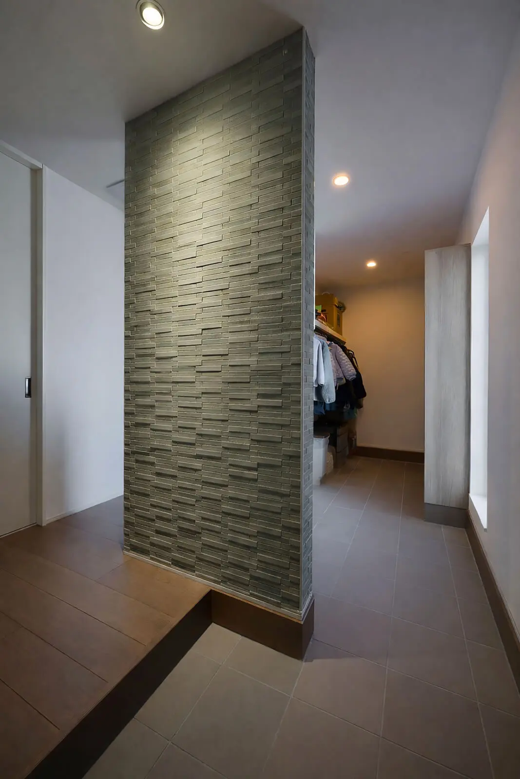 6帖の玄関は壁で手前の客用と奥の家族用に分かれている。壁に張られているエコカラットは調湿・脱臭などの機能があり、意匠としてだけでなく、玄関では気になる臭いの対策にもなる