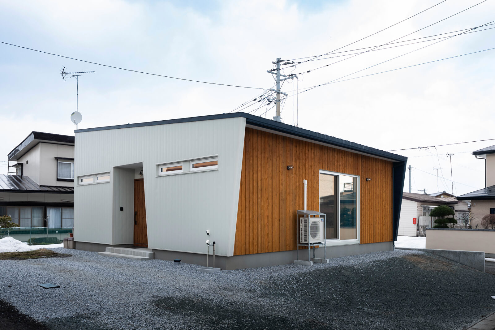 オフホワイトのガルバリウム鋼板とレッドパイン材の木外壁を組み合わせた、爽やかな雰囲気のIさん宅。玄関や南面にデザインした斜めのラインがおしゃれ