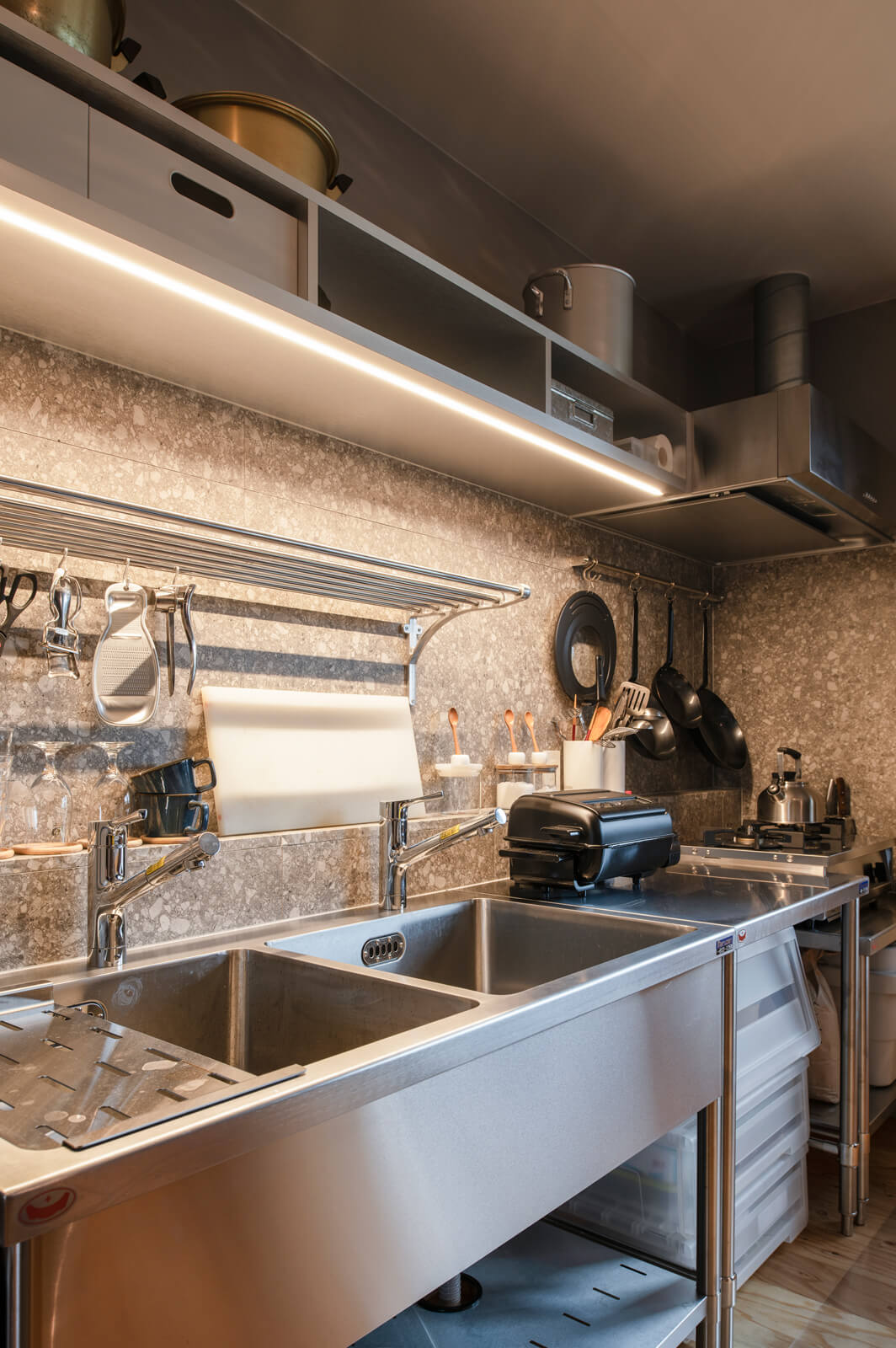 メンテナンスがしやすく、使い勝手の良いステンレス製の業務用設備を採用したキッチン。壁にはタイルを張り、間接照明も設置