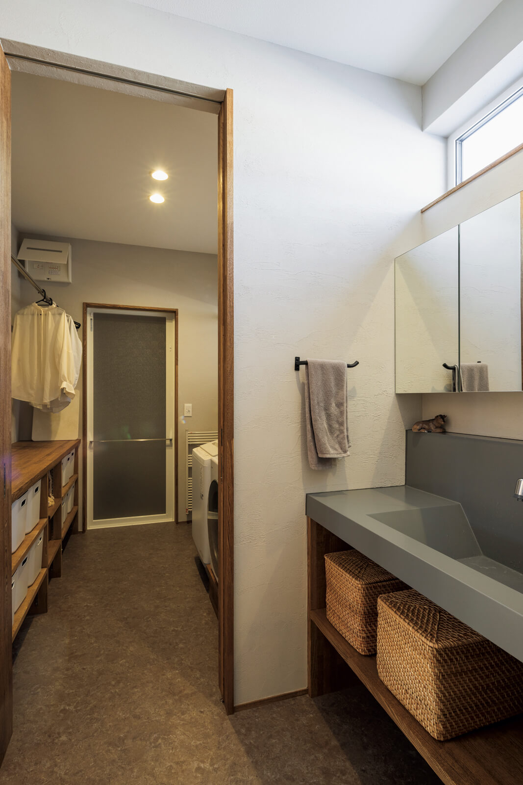 造作仕様の独立型洗面台奥は洗濯脱衣室。カウンター収納を造作し、衣類乾燥機も洗濯物を出し入れしやすい高さにこだわった