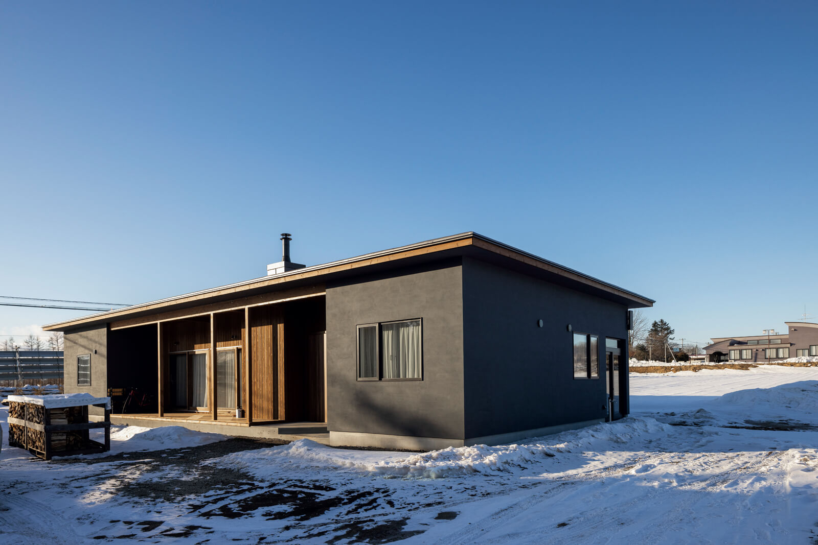 横に長く高さのある塗り壁と木板張りの外観が、重厚な雰囲気を漂わせるOさん宅