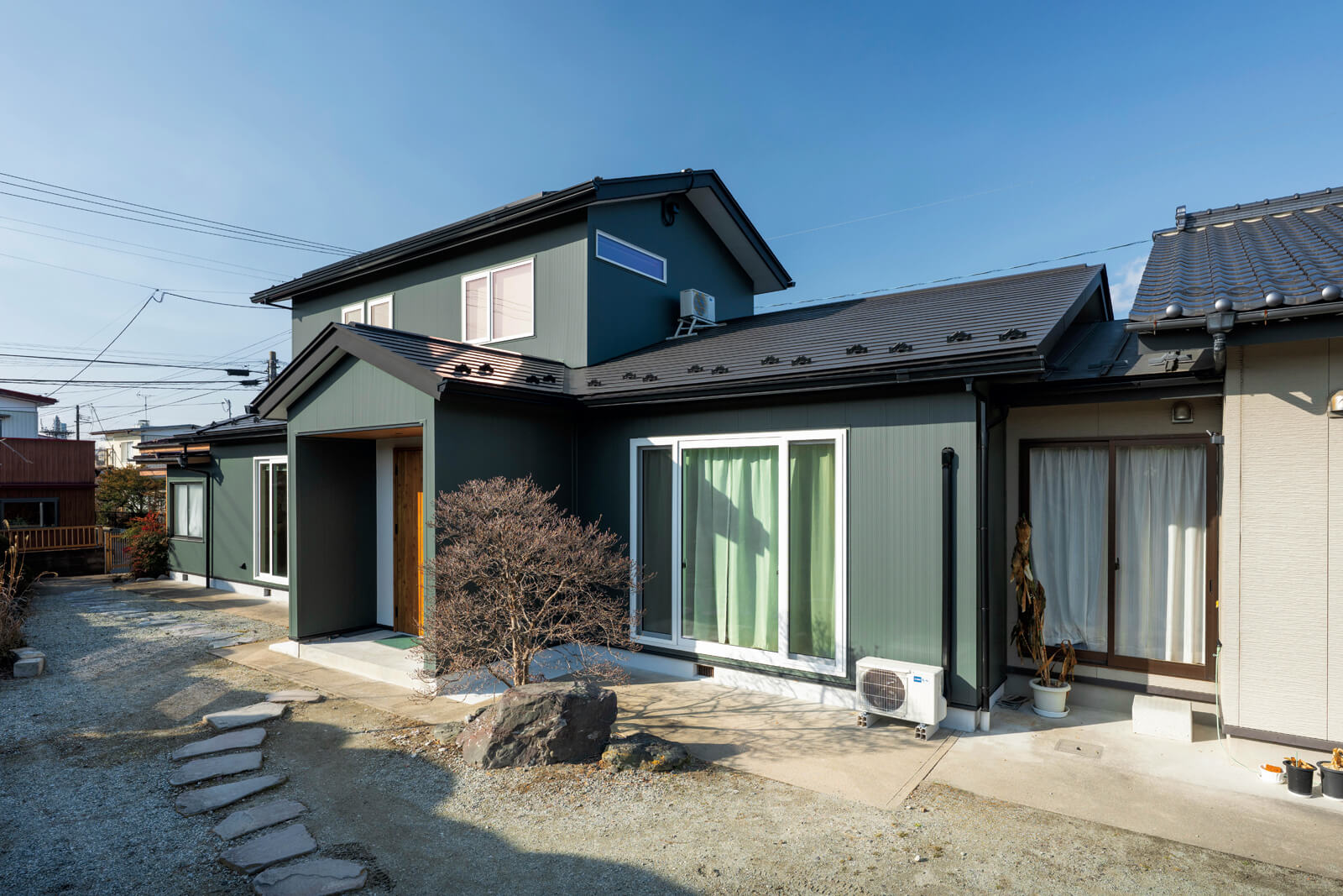 外壁材にグリーンのガルバリウム鋼板を用いて、外観の印象を刷新。玄関ポーチの上部は三角屋根につくり変えた