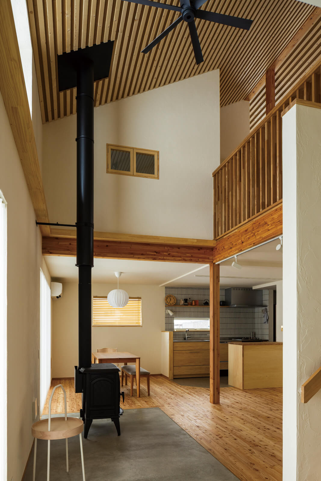 土間に設けた薪ストーブの奥にダイニングとキッチンが続き、吹き抜けを介して2階ともつながる住まいの中心空間。トドマツ板張りの勾配天井が、温かみと心地よい広がりをもたらしている