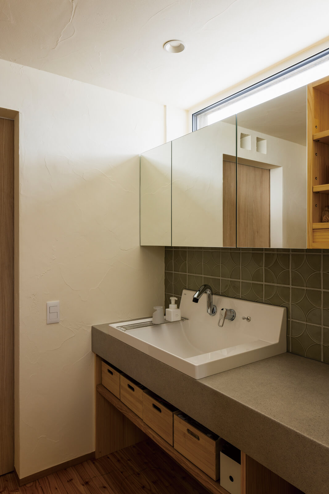 ハイサイドライトから自然光を取り込む洗面スペース。掃除のしやすさに配慮し、壁付け水栓を設けた