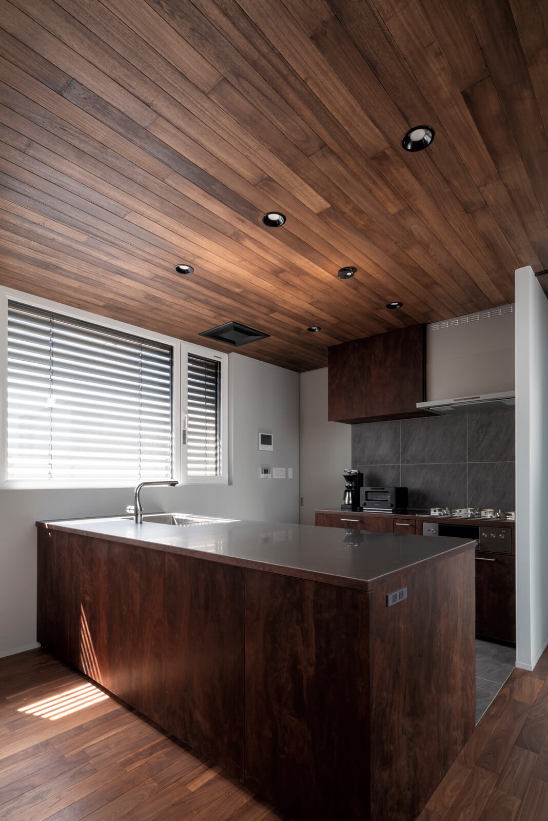 オープンな造作の対面キッチンは二列型で、ガスレンジは壁側に配した