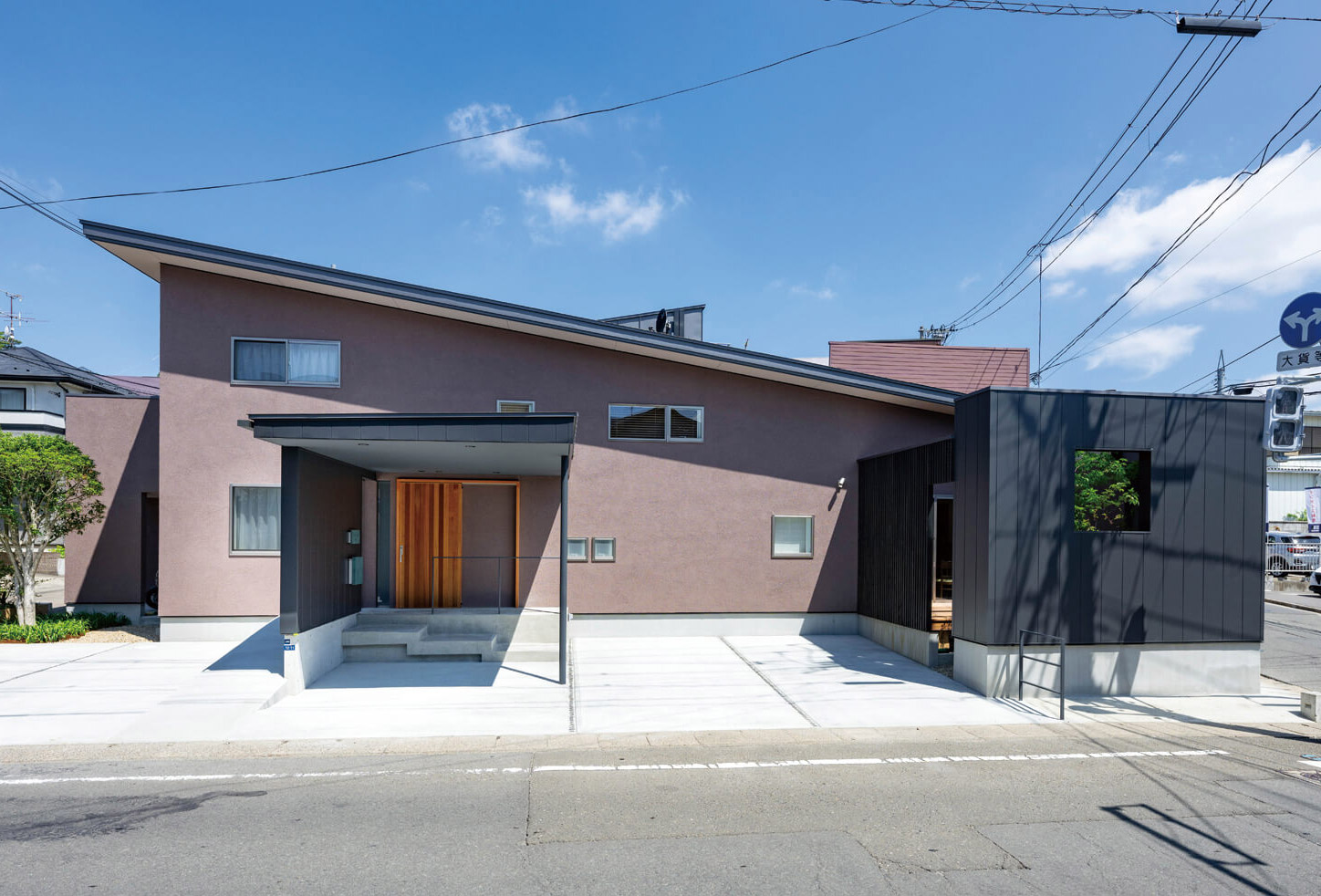 片流れの大屋根と塗り壁、リビング前のコート(中庭)を囲む金属壁の組み合わせが特徴的な南側の外観