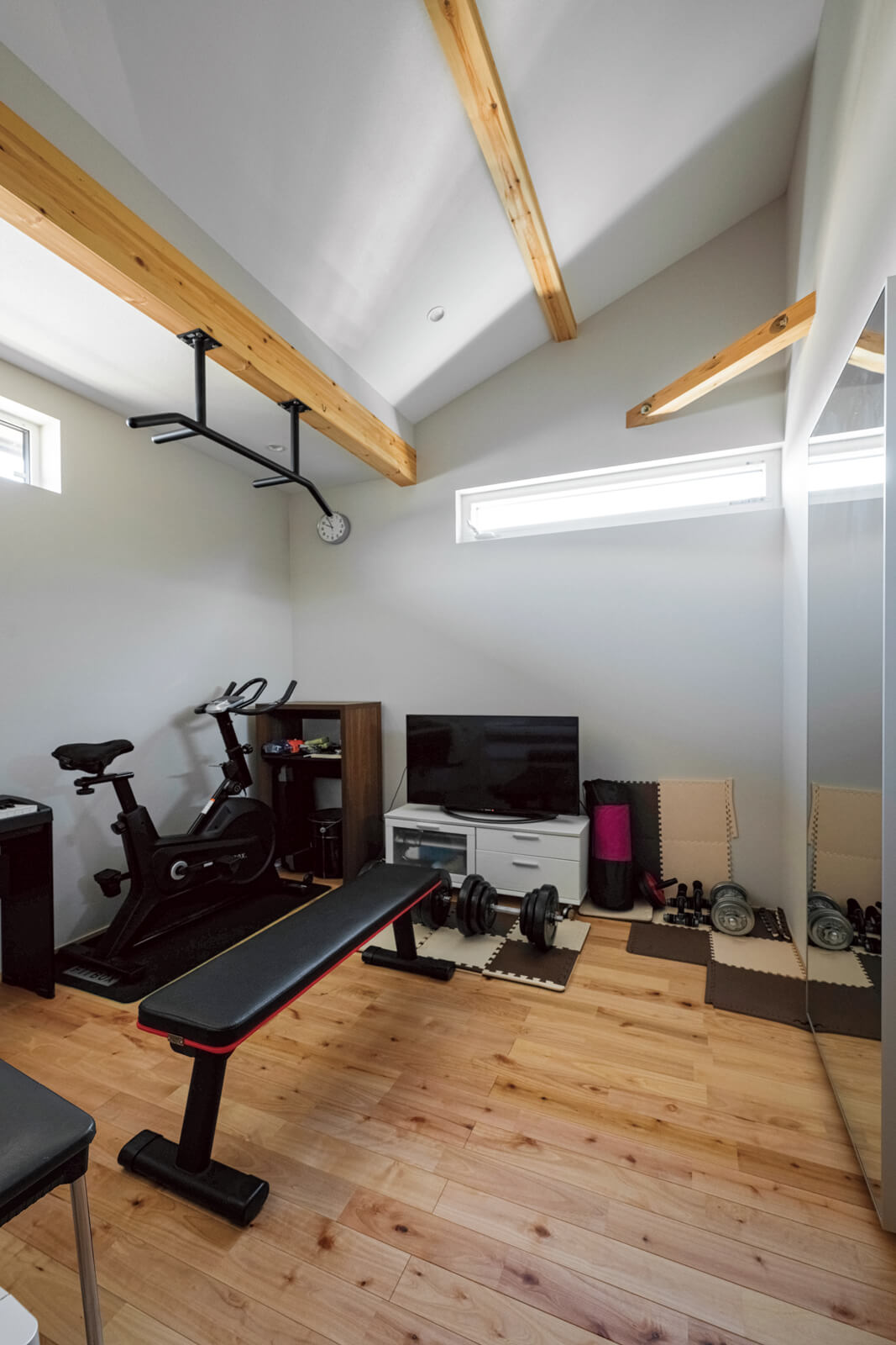 屋根なりの勾配天井で天井高のある5.5帖のフリールーム。電子ピアノや筋トレ器具を置いて、趣味部屋として活用している