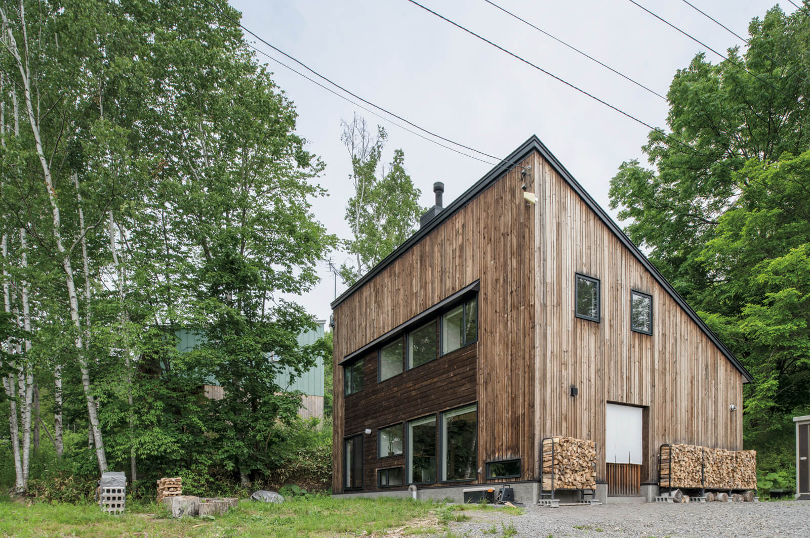 シラカバやミズナラが自生する緑豊かな敷地に立つKさん宅。ダイナミックな片流れ屋根とカラマツ材を用いた外壁が人の目を引く
